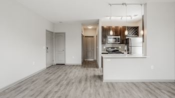 A kitchen with a white countertop and stainless steel appliances is visible through a glass door